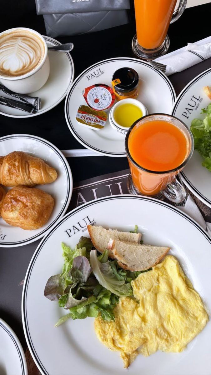 an assortment of breakfast foods and drinks are on the table with coffee, croissants, orange juice, and croissant