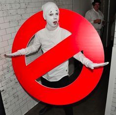 a man dressed in white holding a red no entry sign