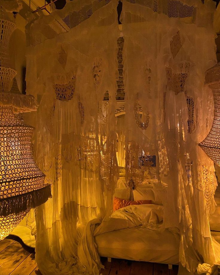 a bed with white sheets and curtains hanging from the ceiling