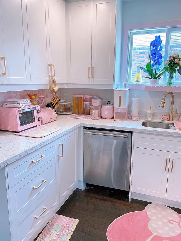 a kitchen with white cabinets and pink accessories on the counter top, including a dishwasher