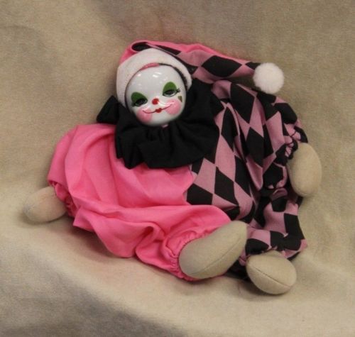 a stuffed animal is dressed in pink and black checkerboard with a clown mask