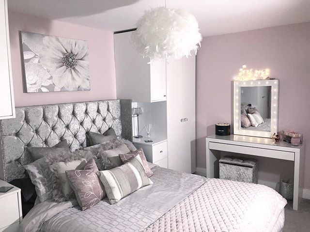 a bedroom with a bed, dresser and dressing table in the corner is decorated in silver and white