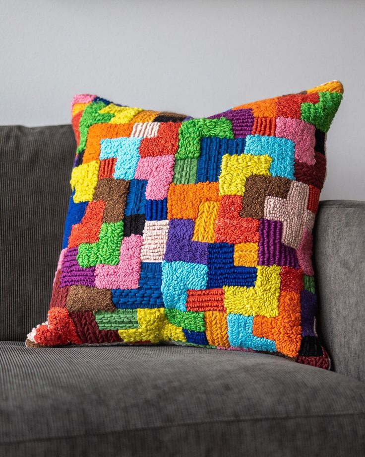 a multicolored pillow sitting on top of a gray couch