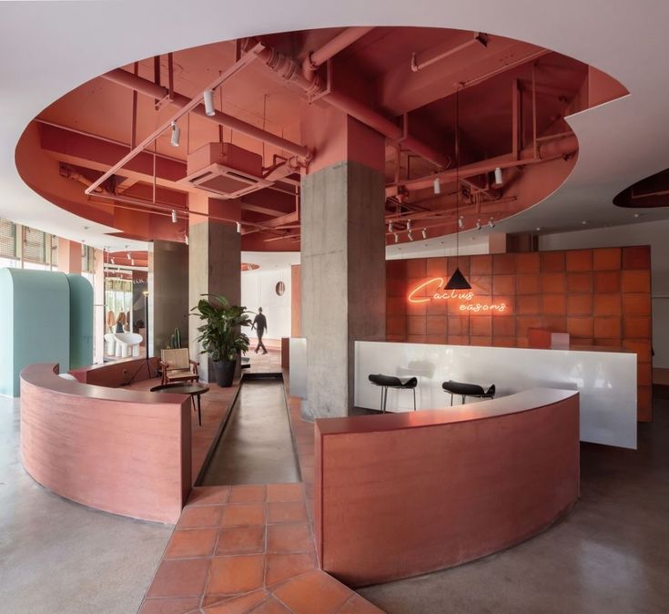 the inside of an office building with orange and white walls, large curved desks and chairs