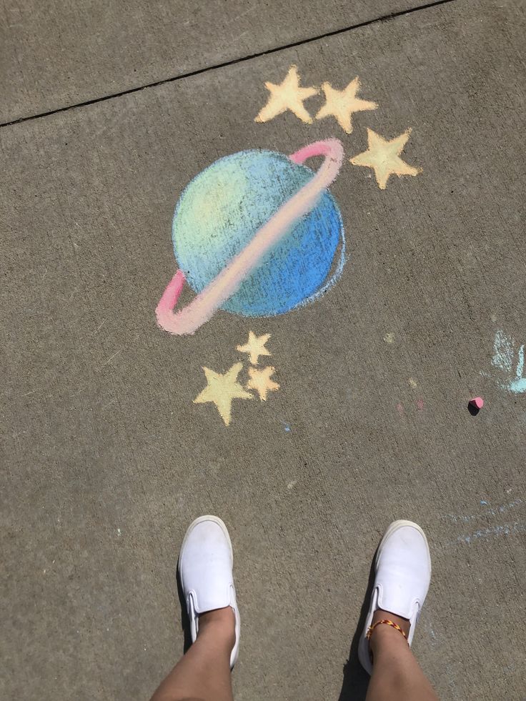 someone is standing on the sidewalk with their feet in front of chalk drawings and stars