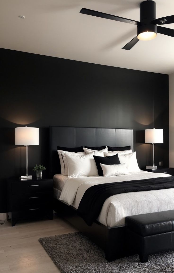 a black and white bedroom with a large bed, two lamps, and a ceiling fan