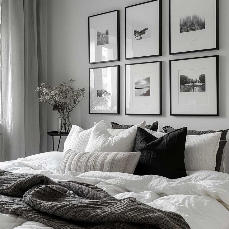 a bed with white sheets and pillows in front of pictures on the wall above it