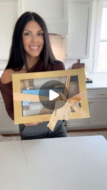 a woman sitting at a kitchen table holding up a photo frame with an image on it