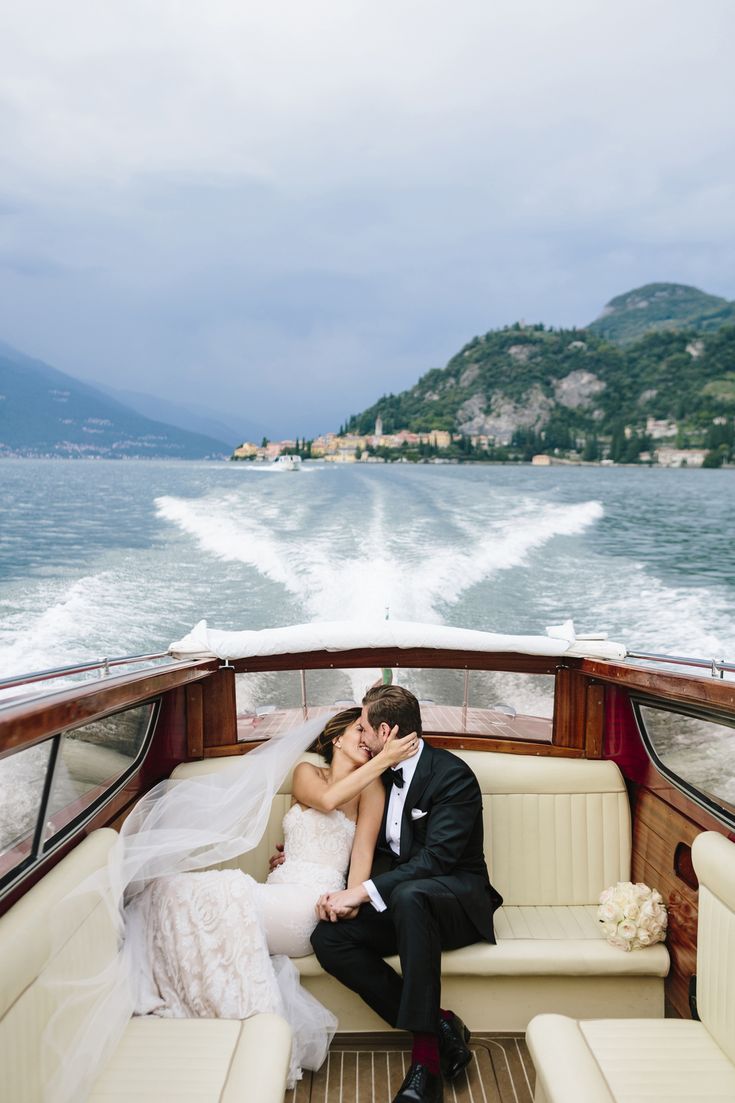 a bride and groom sitting on the back of a boat