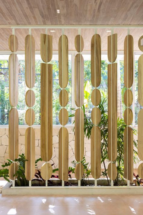 a room divider made out of wooden planks with plants in the center and windows behind it