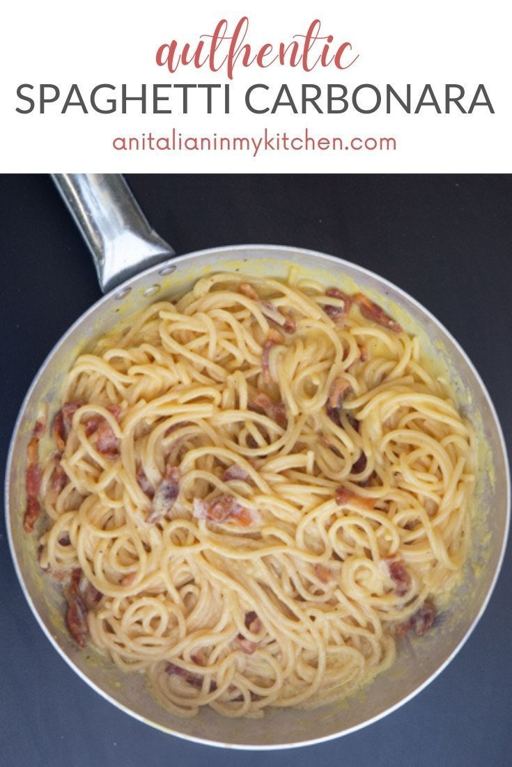 a pan filled with pasta on top of a black counter next to a silver spoon