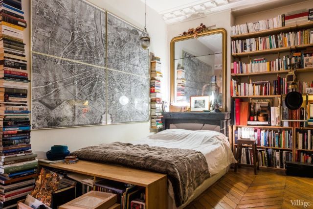 a bed sitting in a bedroom next to a book shelf filled with books on top of a hard wood floor