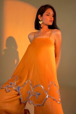 Orange spaghetti strap sleeves kurta with flora cutwork embroidery on the hem using sequin, bead highlights. Paired with a flared sharara. - Aza Fashions Embellished Georgette Sharara For Summer, Designer Spring Dresses With Gota Work, Silk Sharara For Designer Wear In Summer, Designer Silk Sharara For Summer, Elegant Summer Sharara With Gota Work, Summer Silk Sharara With Sheer Dupatta, Summer Sharara With Dupatta, Silk Floor-length Sharara For Summer, Summer Wedding Sharara With Gota Work