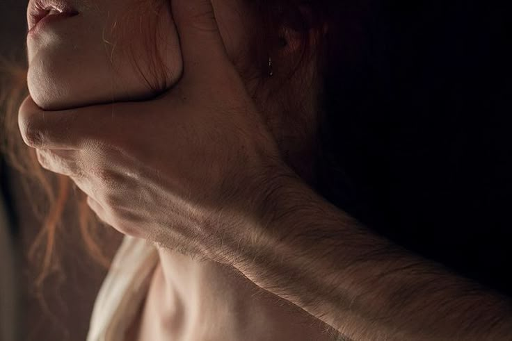 a woman holding her hand up to her face while she is looking out the window