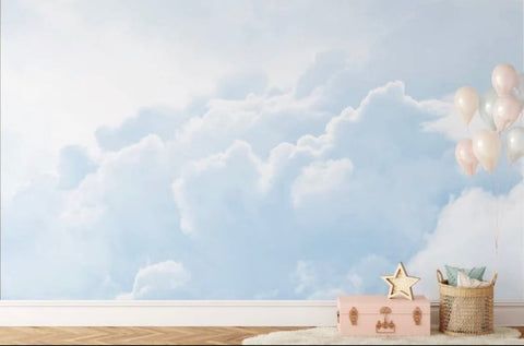 a baby's room with clouds and stars painted on the wall, including a pink trunk