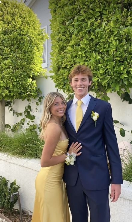 a man and woman in formal wear standing next to each other smiling for the camera