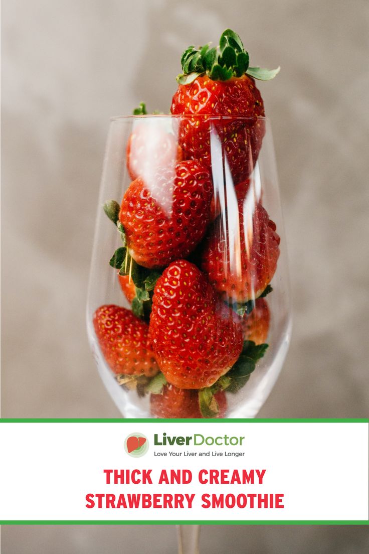 a glass filled with strawberries on top of a table