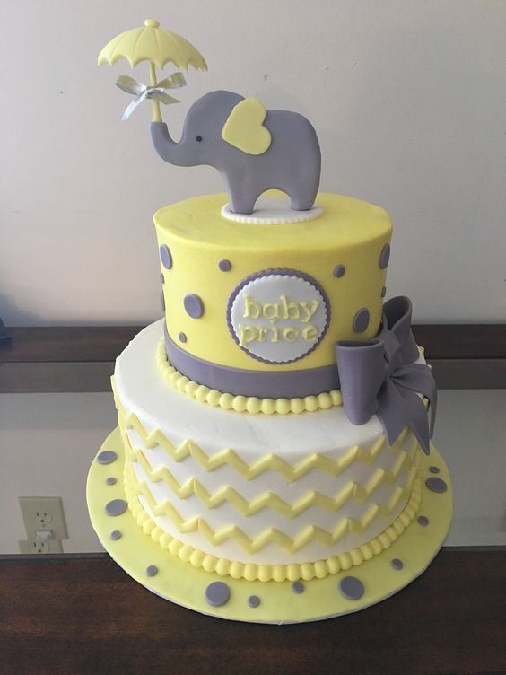 a yellow and gray cake with an elephant on top that says baby boy in the middle