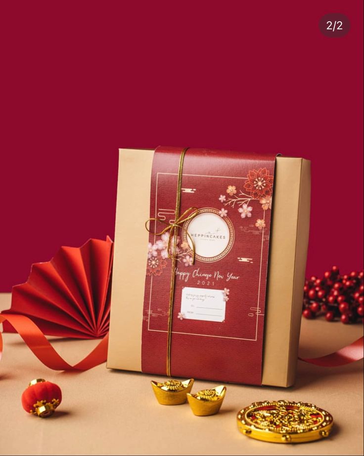 a red and white gift bag next to some gold candies on a brown table