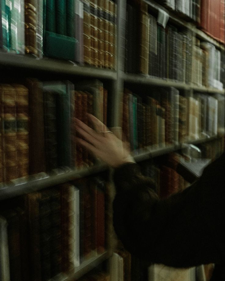 a person reaching for books in a library