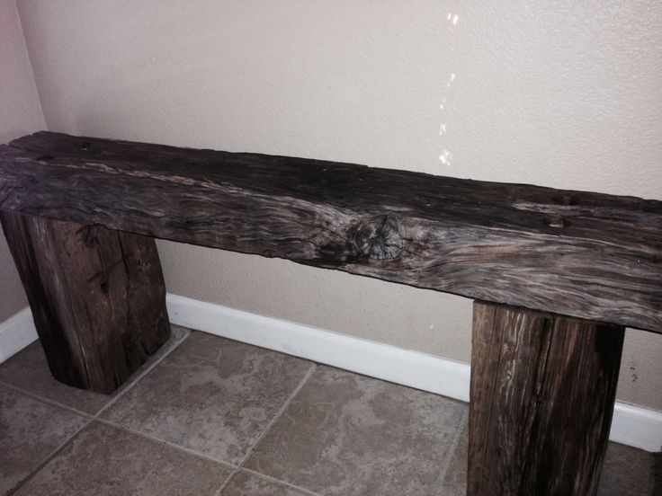 a wooden bench sitting in the corner of a room next to a wall and tile floor