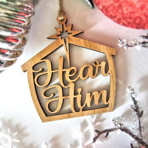 a wooden ornament with the words hear him and a star hanging from it