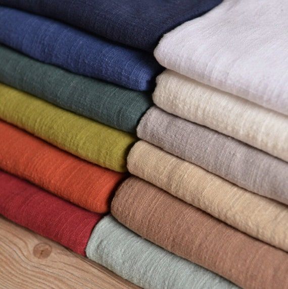 a stack of folded linens sitting on top of a wooden table next to each other