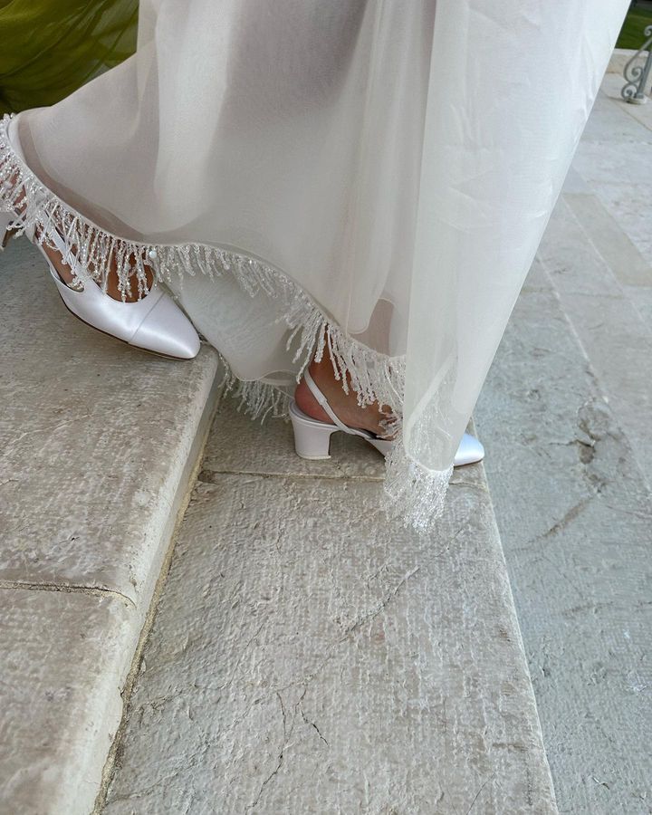 a woman's feet in white shoes on the sidewalk