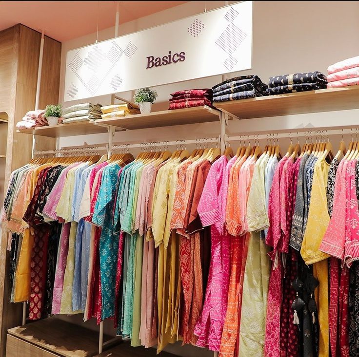 clothes are hanging on racks in a clothing store, with the name basics above them