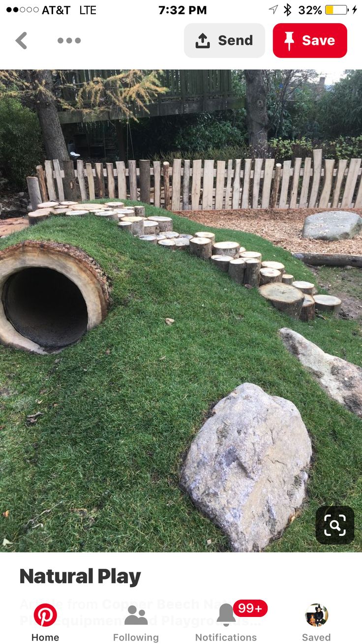 an image of a fake natural play area in the grass with rocks and logs around it