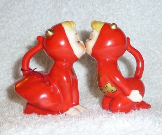 two red ceramic figurines sitting on top of a white carpeted floor next to each other