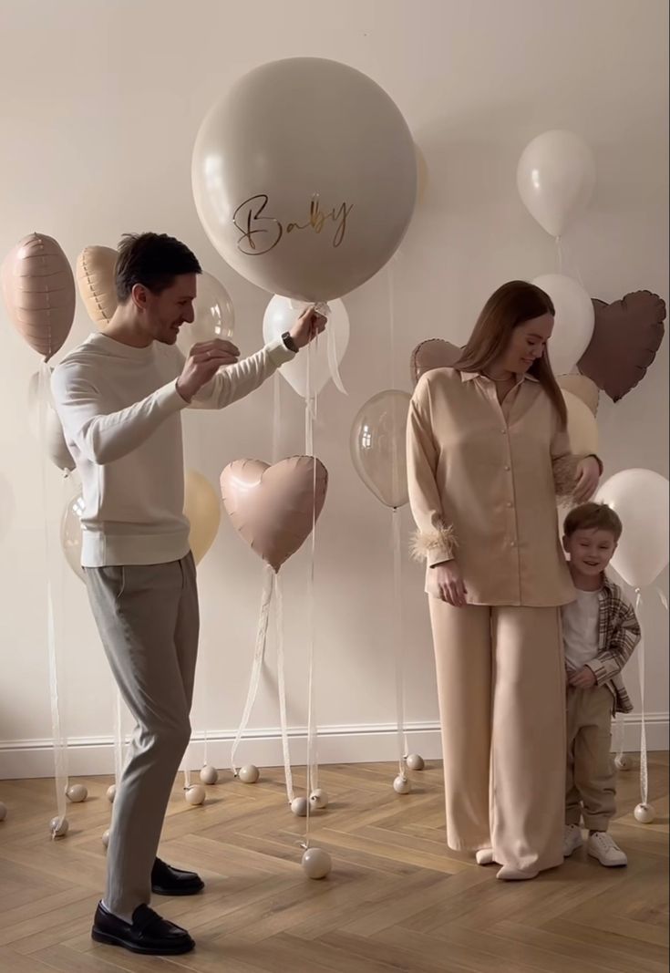 a man and woman standing next to each other with balloons in the shape of hearts