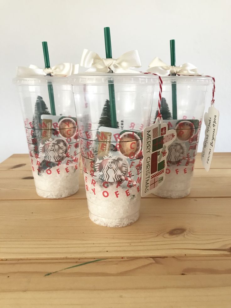 three christmas themed cups with green and red straws in them on a wooden table