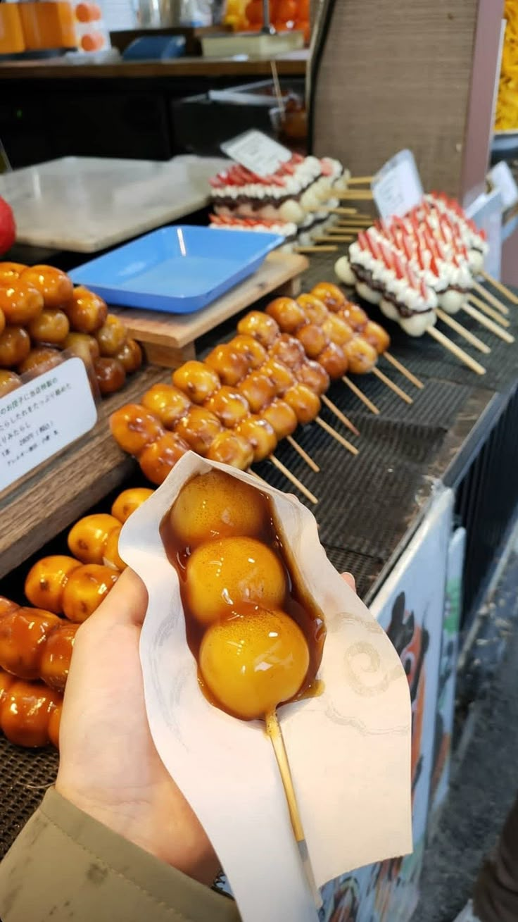 a person is holding a skewer with donuts on it in front of other food items