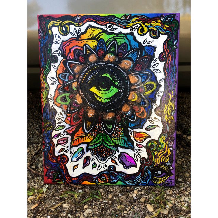 a square painting with an eye surrounded by colorful flowers and leaves on the outside wall