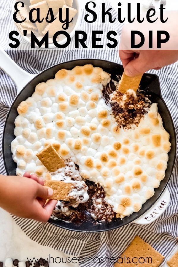 someone dipping graham crackers into a skillet filled with s'mores