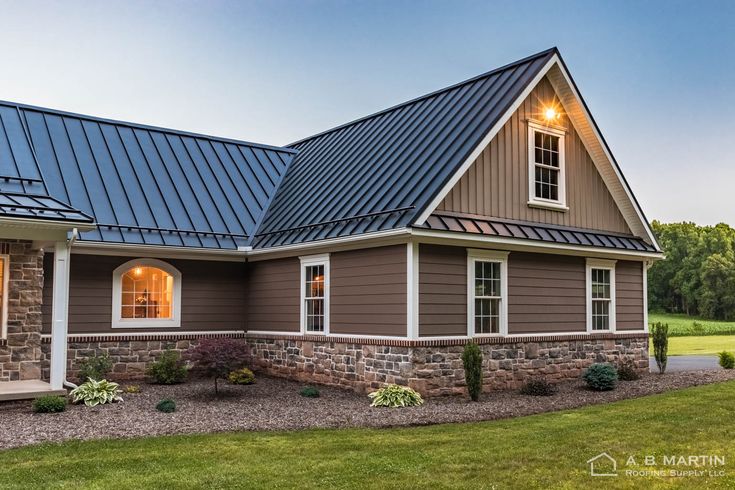 a house that has a metal roof and windows on the side of it, in front of a grassy field