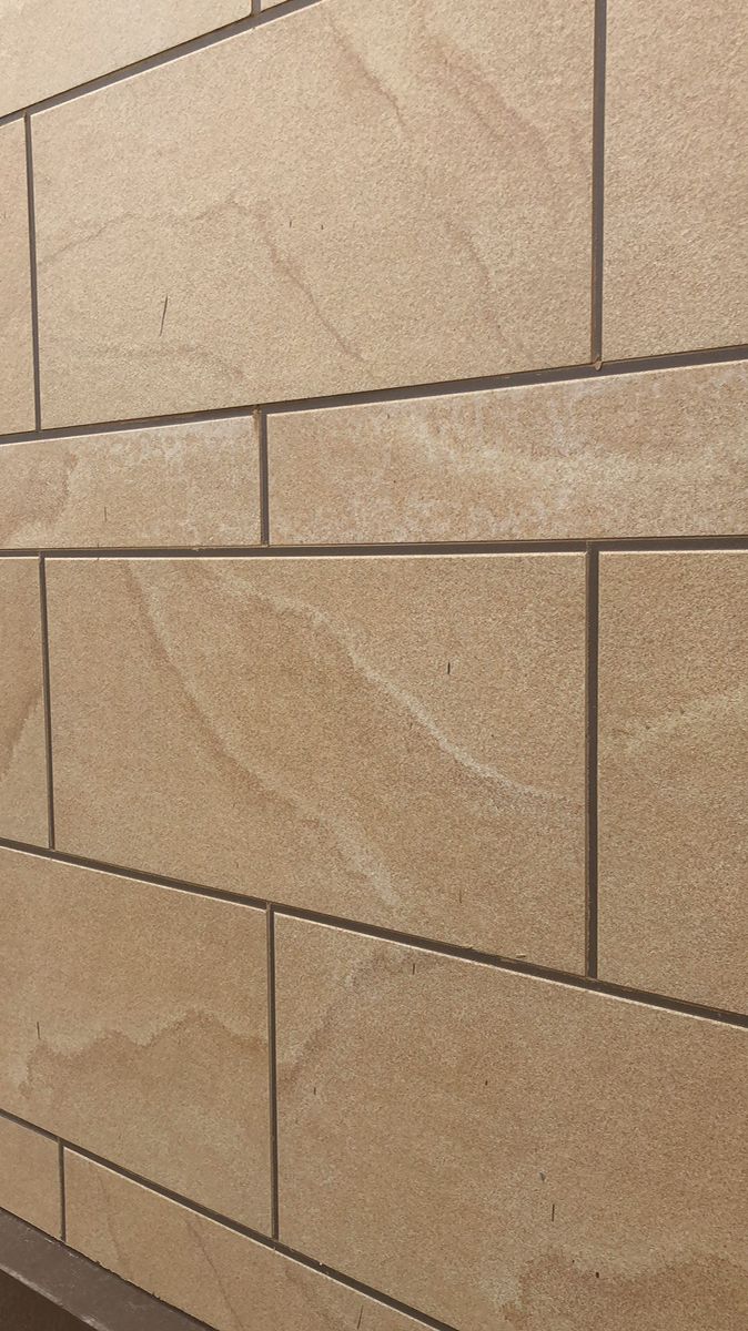 a close up view of a tan brick wall with a bench in the foreground