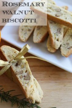 rosemary walnut biscotti on a white plate next to an orange and some bread