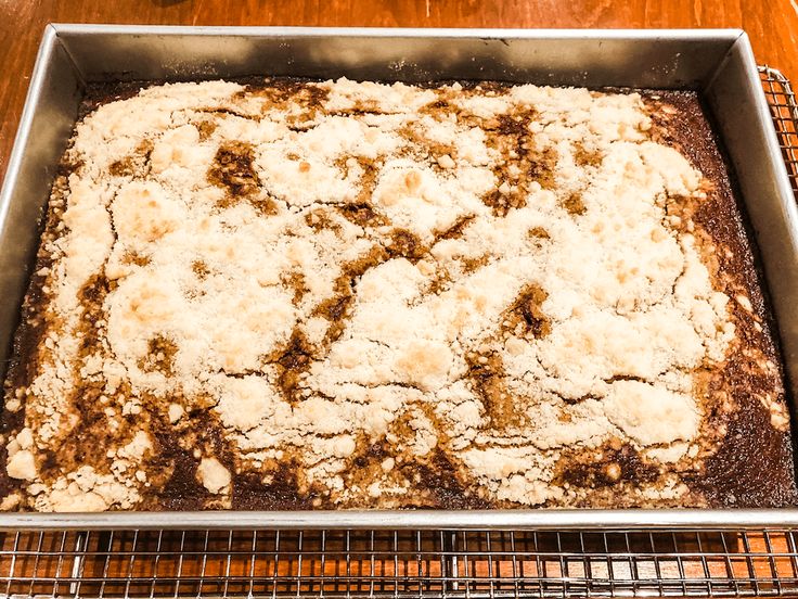 an uncooked cake sitting on top of a metal rack next to a wooden table