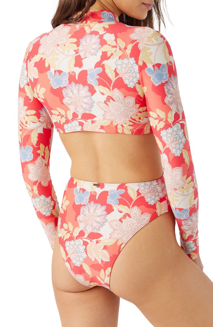 Tropical blooms brings vacation-ready style to this long-sleeve one-piece with sunny waist cutouts. Front zip closure Mock neck Long sleeves Moderate back coverage 85% recycled polyester, 15% elastane Hand wash, dry flat Imported lined Spring Long Sleeve Surfing Bodysuit, Long Sleeve Beachy Swimwear For Pool, Long Sleeve Tops For Pool And Spring, Beachy Long Sleeve Tops For Poolside, Long Sleeve Floral Print Swimwear For Surfing, Summer Long Sleeve Tops For Poolside, Fitted Long Sleeve Swimwear For Beach Season, Long Sleeve Summer Tops For Poolside, Spring Long Sleeve Tops For Poolside