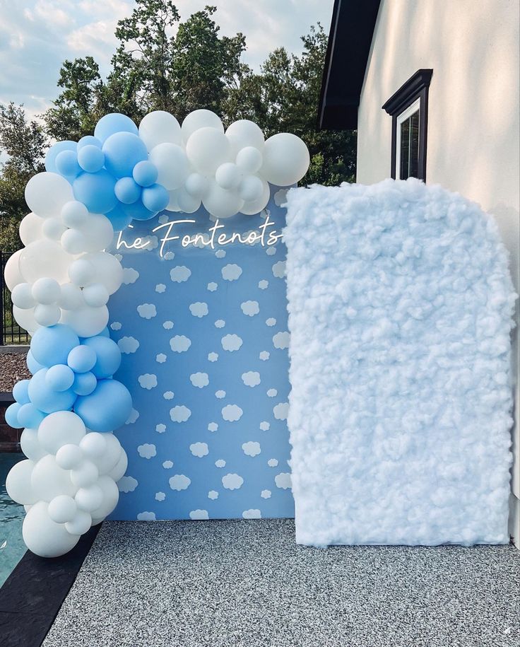 a blue and white backdrop with balloons in the shape of an arch for a wedding ceremony