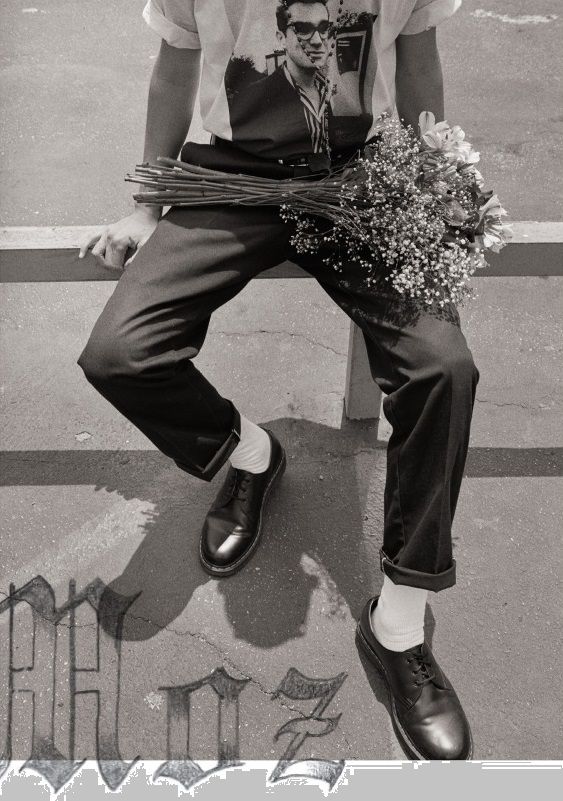 black and white photograph of a man sitting on a bench with flowers in his lap