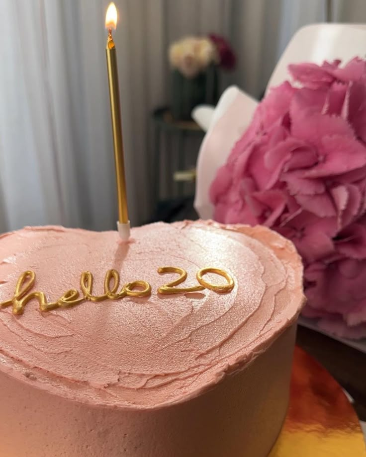 a pink cake with the word hello - 22 on it and a single lit candle