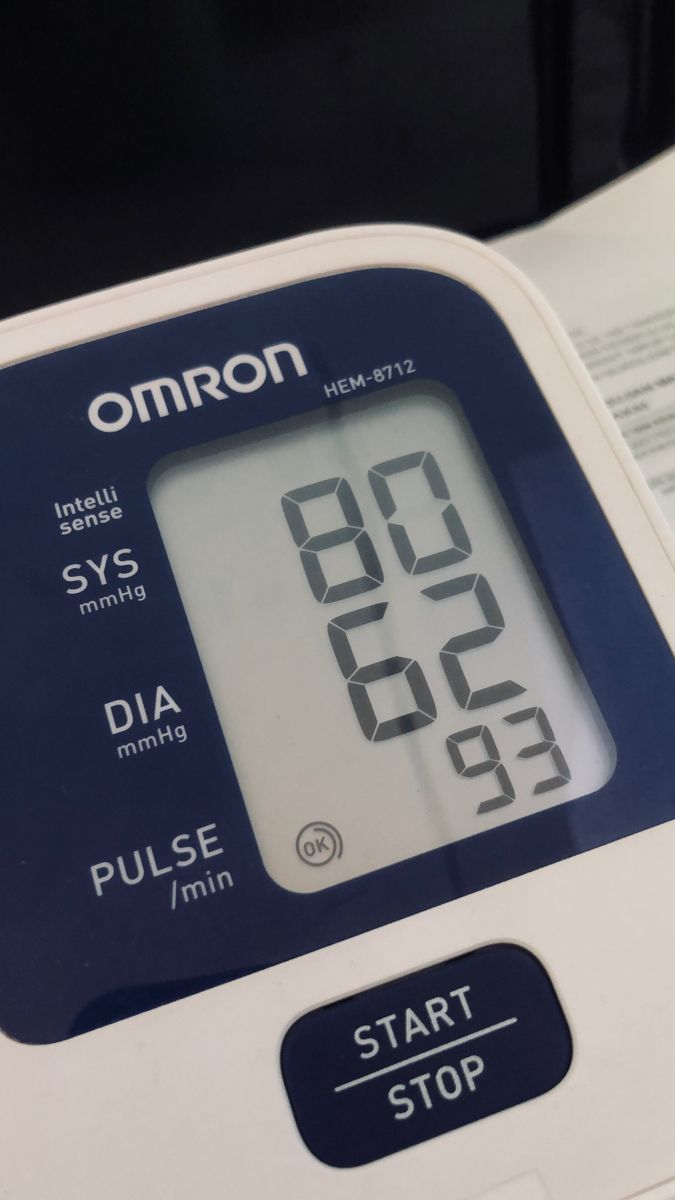 an omron digital blood pressurer with instructions on the front and back side, in use