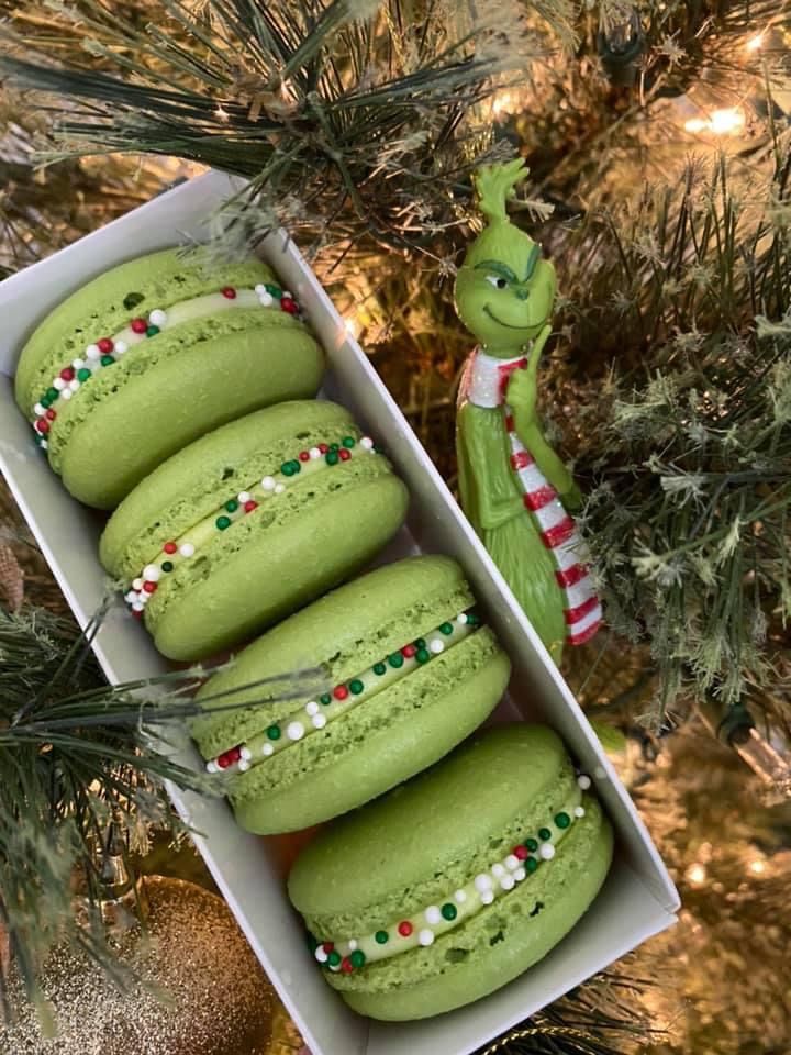 some green macaroons are in a box on the christmas tree and one is decorated with candy