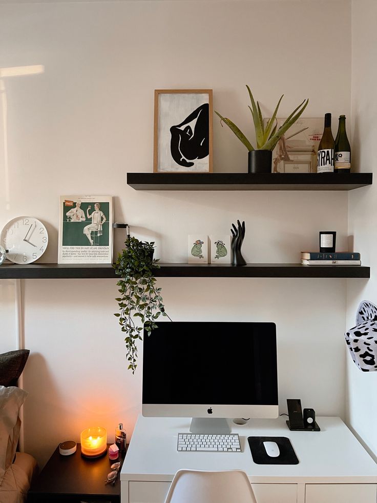 a white desk with a computer on top of it next to a plant and candles