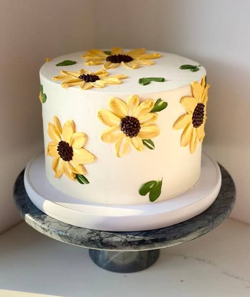 a white cake with sunflowers painted on it