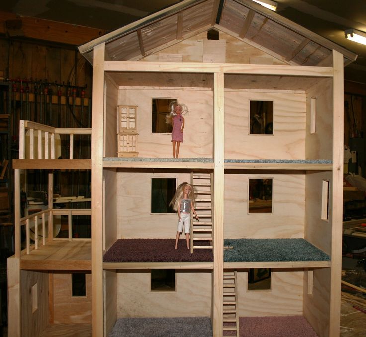 a doll is standing on top of a house made out of plywood and wood