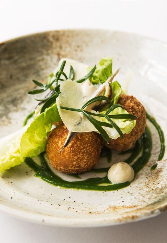 a white plate topped with meatballs covered in sauce and garnished with lettuce